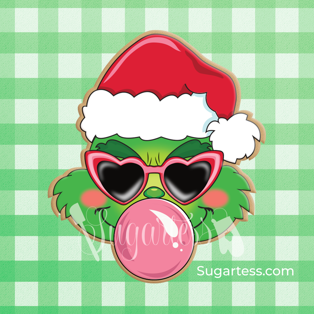 Sugartess custom cookie cutters in shape of Grinch's head wearing a Santa Claus hat and blowing a bubblegum.