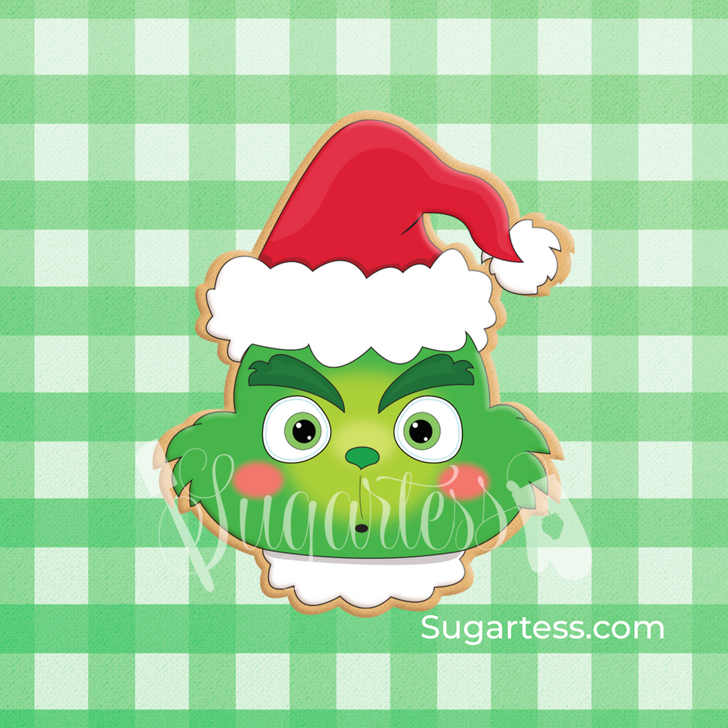 Sugartess custom holiday cookie cutter in shape of cartoon Grinch head with winter Santa hat.