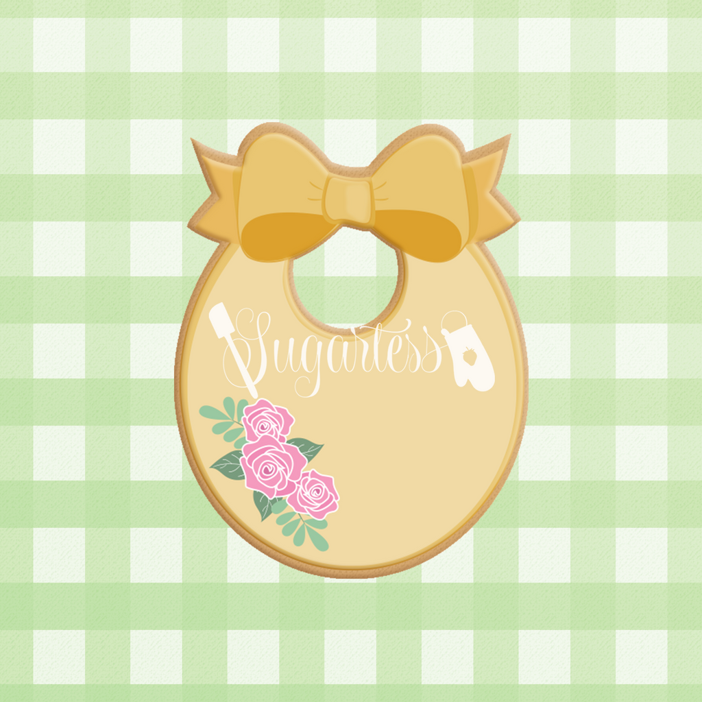 Sugartess custom cookie cutter in shape of oval-shaped baby bib with large bow on top.