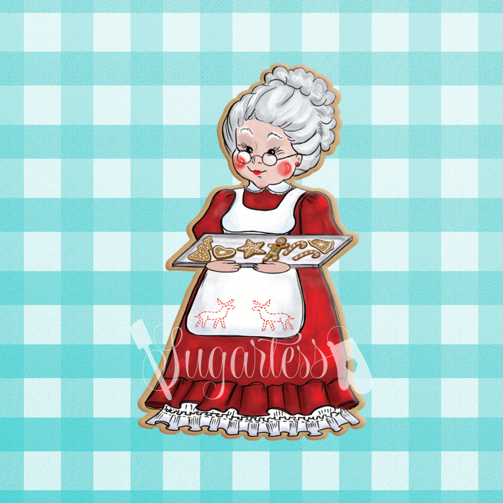 Sugartess custom Christmas cookie cutter in shape of Mrs. Claus holding a tray of decorated holiday cookies.