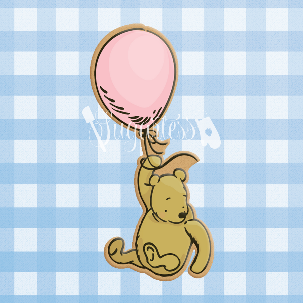 Sugartess custom cookie cutter in shape of classic Winnie The Pooh bear flying holding a balloon.
