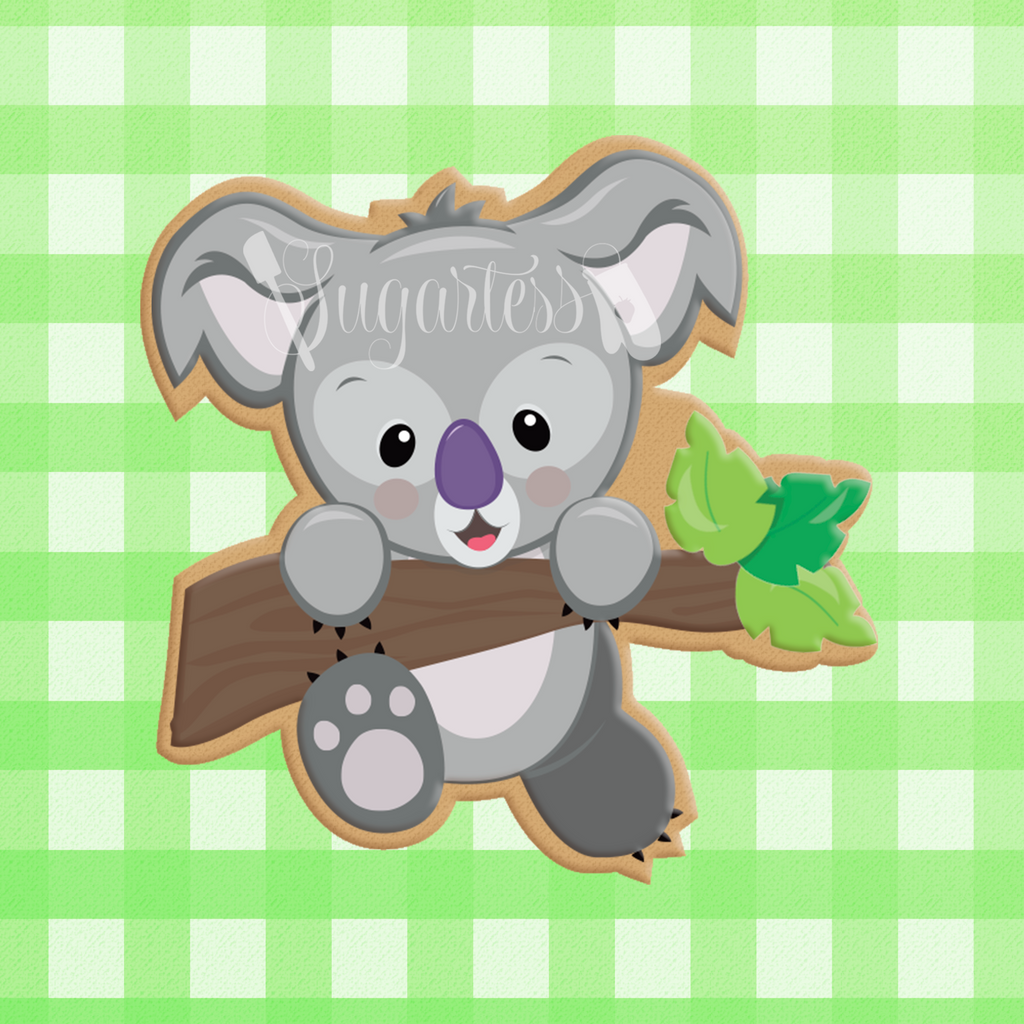 Sugartess custom cookie cutter in shape of koala bear hanging on tree branch.