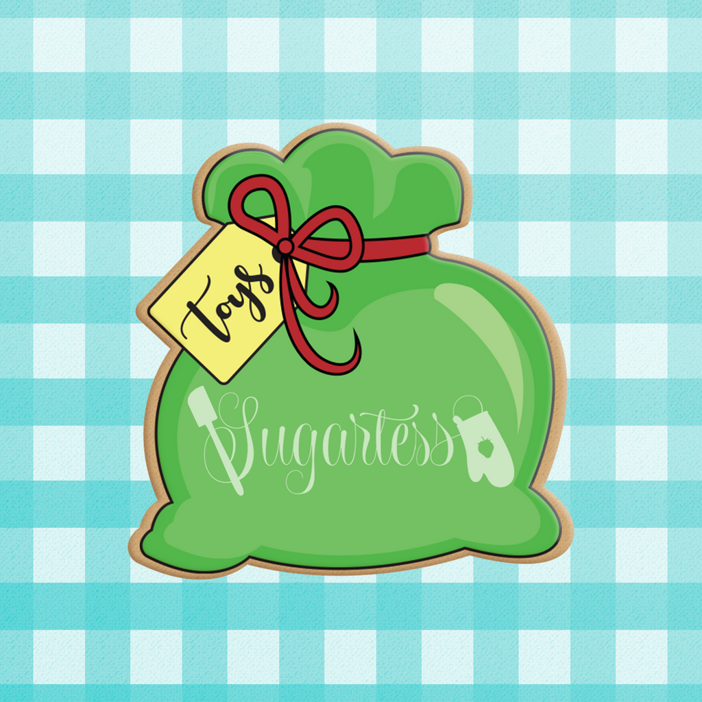Sugartess Christmas cookie cutter in shape of Santa's toy bag tied with a ribbon and with a tag.
